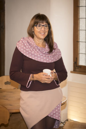 Pull au ton lie-de-vi avec large col aux imprimés étoiles géométriques mauve, porté avec une jupe rose argile, en jersey épais