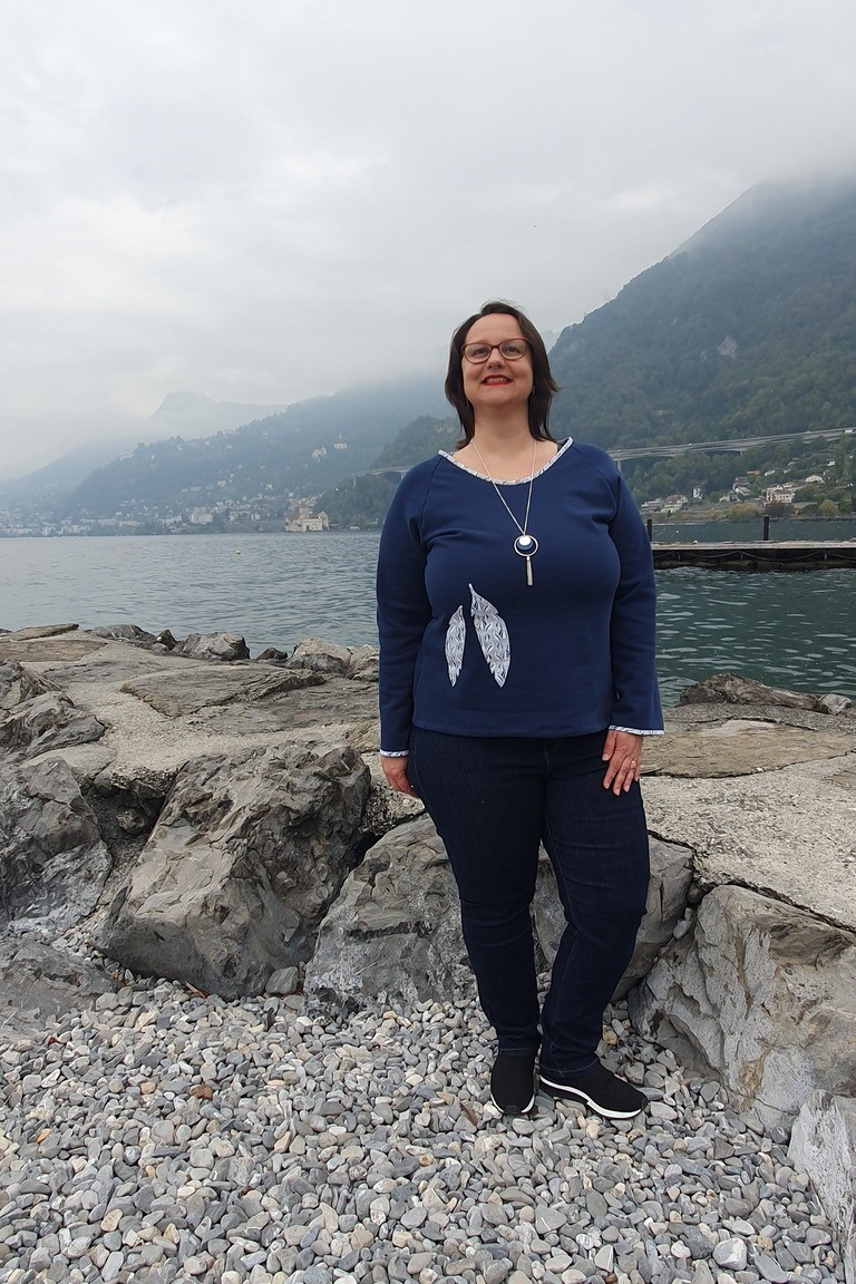 Pull de la gamme Patch'mode, en bleu denim, et motif plumes sur le devant assorti au biais de l'encolure